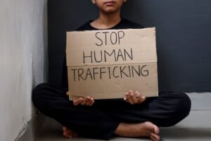 Featured Image Copy: A young person holding a sign saying “Stop human trafficking.” Survivors who need counseling and resources for human trafficking in Orange County can find out more here.